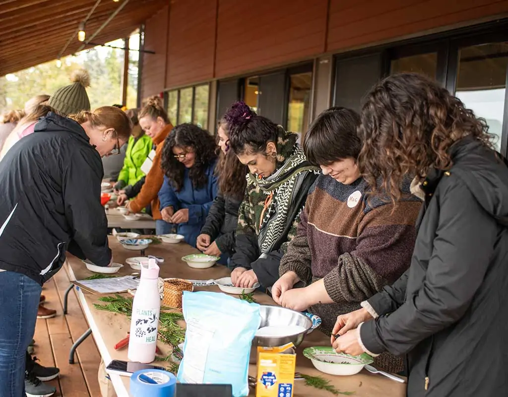 group of people doing hands on cooking activity around table on porch