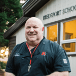 man in black shirt stands in front of Reedsport School District office