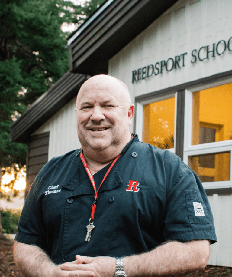man in black shirt stands in front of Reedsport School District office