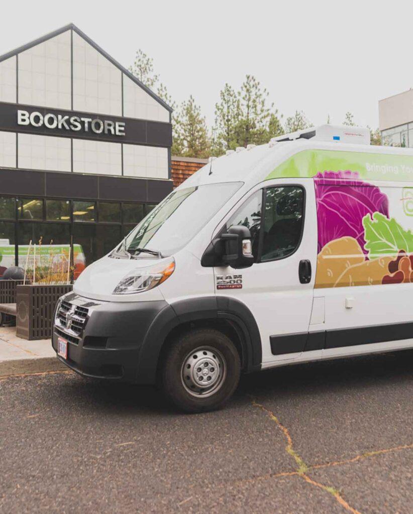 A vegetable delivery van parked in front of a bookstore
