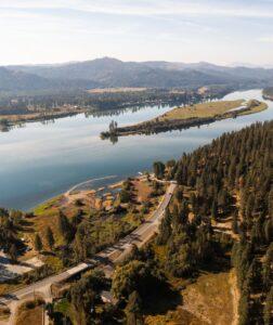 a drone image of the large Pend Oreille river with trees and a road in the lower third of the image