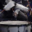 close up of drum being played with feathered sticks, indigenous community image