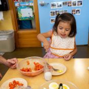 young child eating fresh fruits indoors, classroom setting