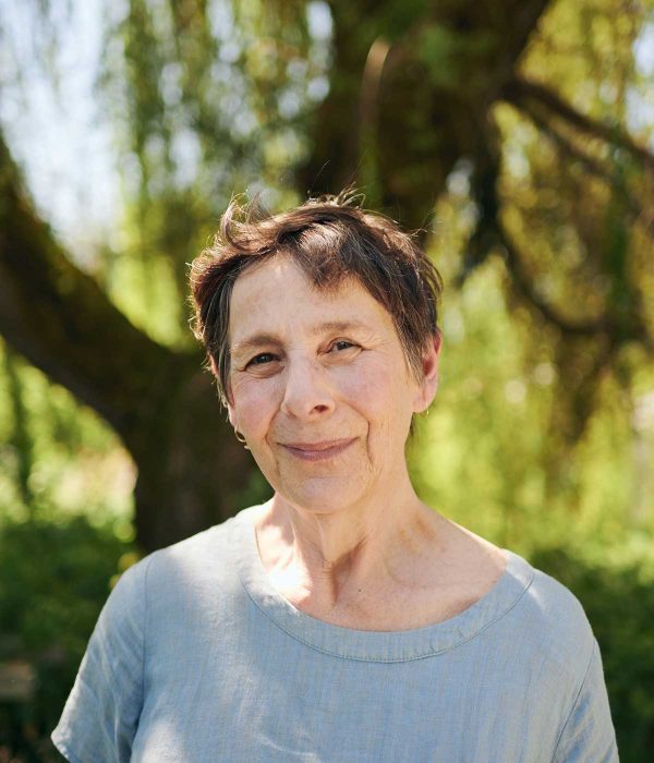 Person smiling at camera outside under a tree