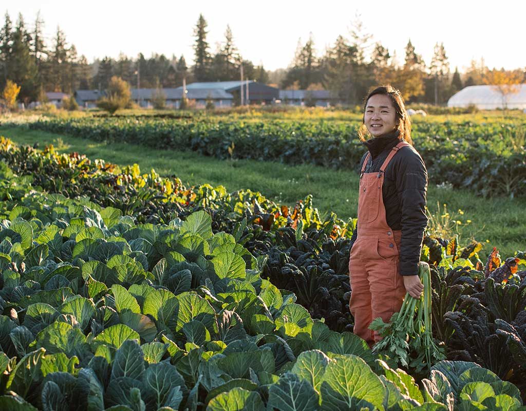 Catherine Nguyen stands in a field of leafy greens