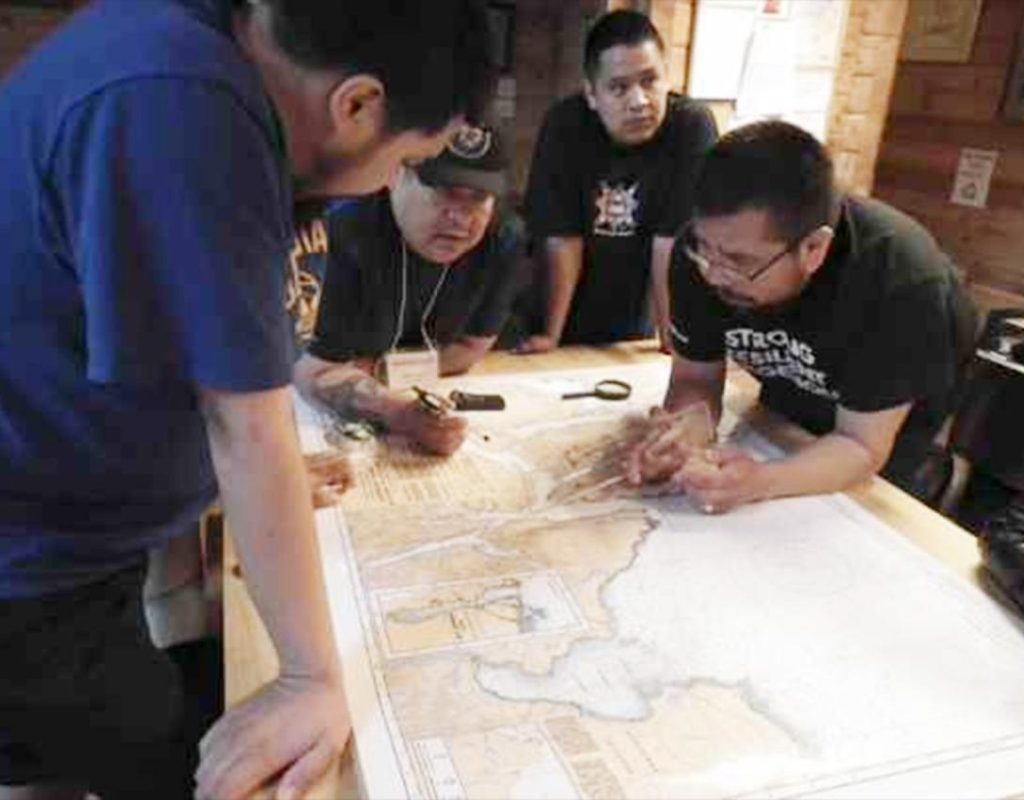 Four men in discussion as they around a map on a table