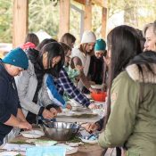 group on adults gathered around a table on a farm doing an activity