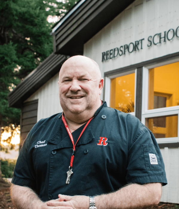 man in black shirt stands in front of Reedsport School District office