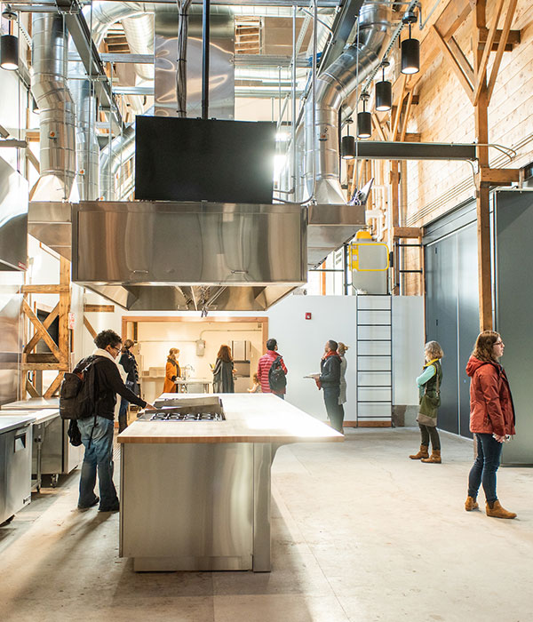 A half dozen adults explore an industrial looking community kitchen space