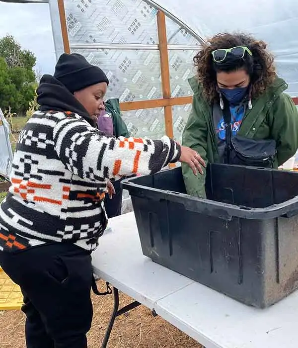 Two people look inside a large plastic bin